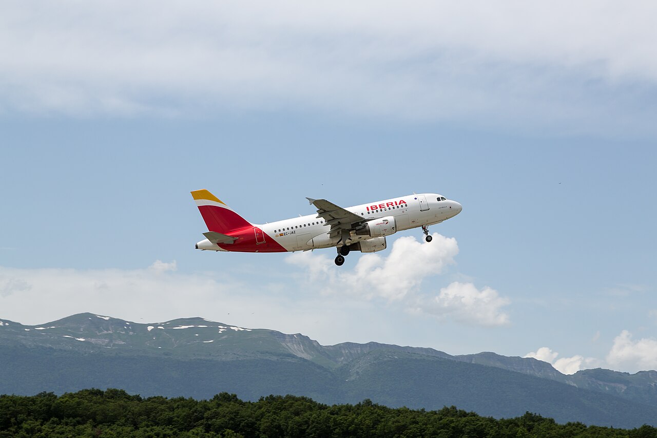 An Iberia Airbus A319 climbing away from Geneva with mountains behind